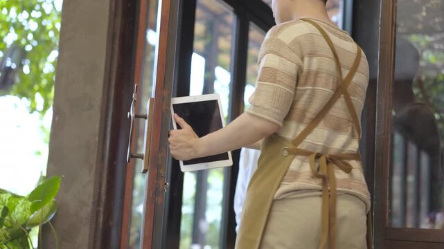 Small business cafe owner guiding young barista, father and son discussing table setup while holding tablet, small business workflow planning and service improvement in cozy restaurant and coffee shop