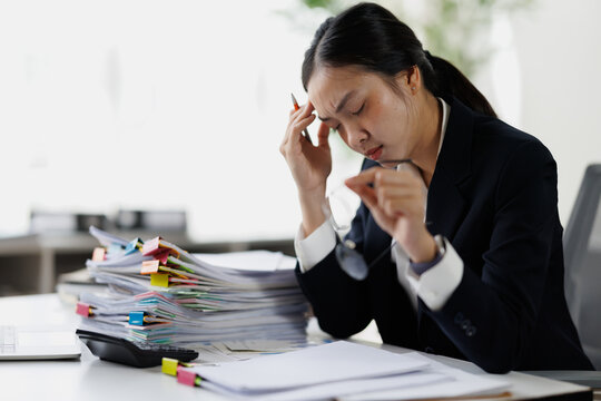 Businesswoman experiencing burnout and headache from overwhelming paperwork