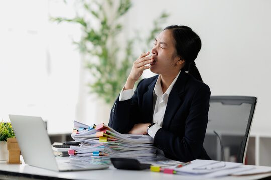 Young businesswoman yawning experiencing work stress and burnout