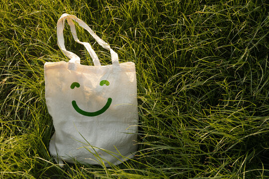 Reusable smiling tote bag on green grass,sustainable lifestyle, eco friendly habits