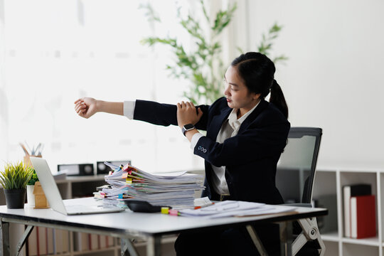 Businesswoman stretching arm, experiencing shoulder pain and office syndrome