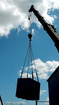 Mobile crane lifting heavy industrial equipment with lifting slings at a construction site. Heavy machinery, logistics, installation and industrial engineering.
