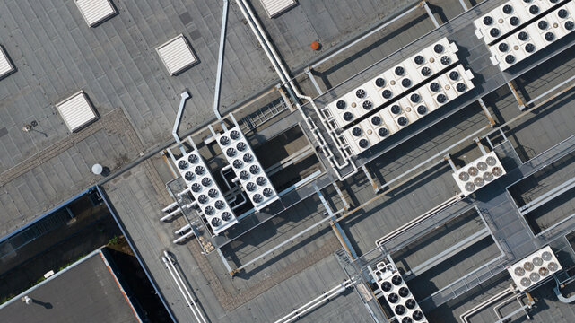 Aerial view of industrial rooftop featuring multiple HVAC cooling fan units, ventilation pipes, and skylights in Nieuwegein, Utrecht, Netherlands.