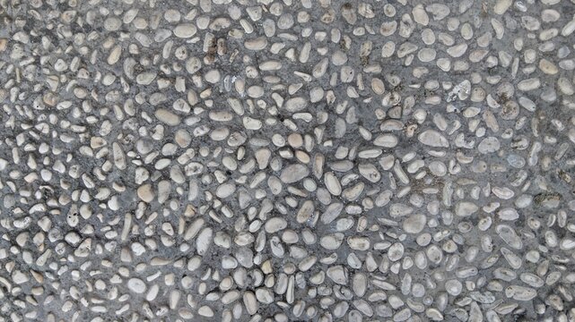 Small white pebble stones embedded in concrete pavement texture background