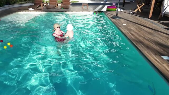 Loving mother and baby enjoying refreshing swimming pool time in peaceful outdoor setting