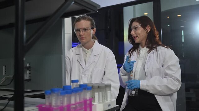 Female Scientists Working in Advanced Research Laboratory with Analytical Equipment and Blue Lighting