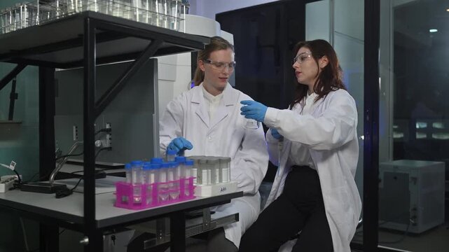 Female Scientists Working in Advanced Research Laboratory with Analytical Equipment and Blue Lighting