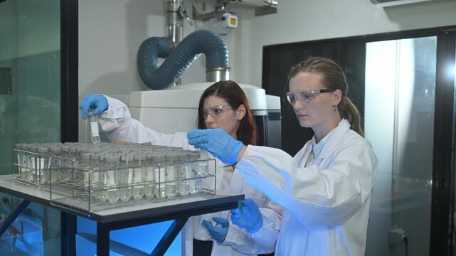 Female Scientists Working in Advanced Research Laboratory with Analytical Equipment and Blue Lighting