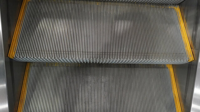 Close-up view of empty metal escalator steps moving inside a building.