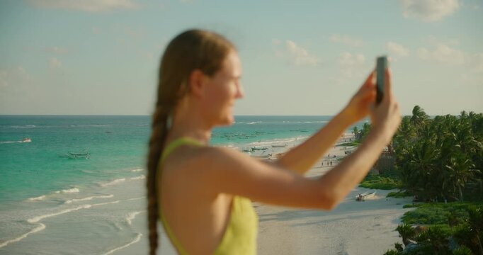 Young woman vlogging with beautiful sandy beach Playa Santa Fe and turquoise ocean on the background in Tulum Mexico
