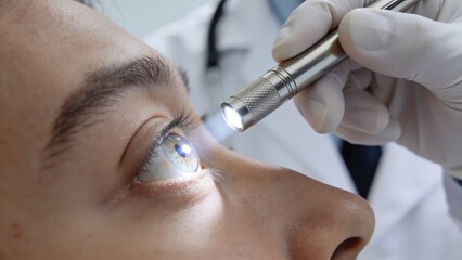 Ophthalmologist Examining Patient Eye with Penlight © PaulStd