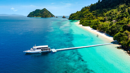 Aerial drone view of tropical landscape over Madam Beach of Nyaung Oo Phee Island with tour boat anchoring on the floating dock in the Mergui Archipelago, Myanmar. Beautiful Andaman sea in Burma © zephyr_p