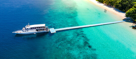 Aerial drone view of tropical landscape over Madam Beach of Nyaung Oo Phee Island with tour boat anchoring on the floating dock in the Mergui Archipelago, Myanmar. Beautiful Andaman sea in Burma © zephyr_p