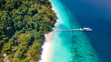 Aerial drone view of tropical landscape over Madam Beach of Nyaung Oo Phee Island with tour boat anchoring on the floating dock in the Mergui Archipelago, Myanmar. Beautiful Andaman sea in Burma © zephyr_p