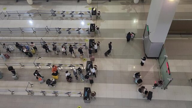 Top view of travelers standing in organized lines inside a busy airport terminal. Perfect for travel, transportation, tourism, and modern lifestyle concepts.