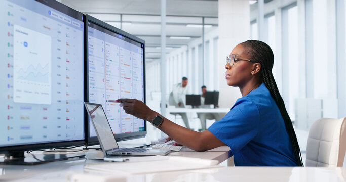 Young African Woman Healthcare Manager Updates Patient Records Using Laptop