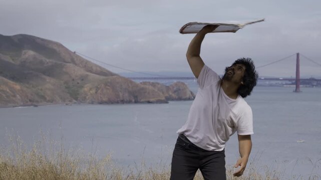 Athlete Spinning And Tossing Large Painted Board Outdoors In Coastal Headland San Francisco - Medium Shot
