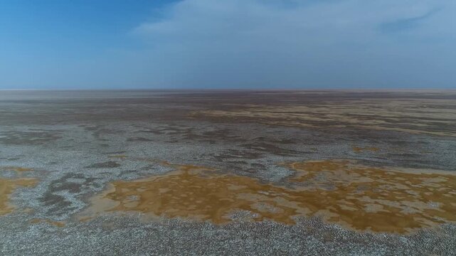 High quality aerial footage of desert salt marsh with cracked earth and scattered water remnants in arid terrain.