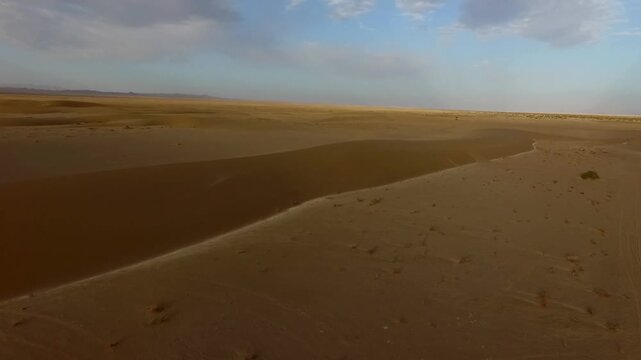 High quality aerial shot showing desert plain with faint vehicle tracks and rolling terrain in arid zone.