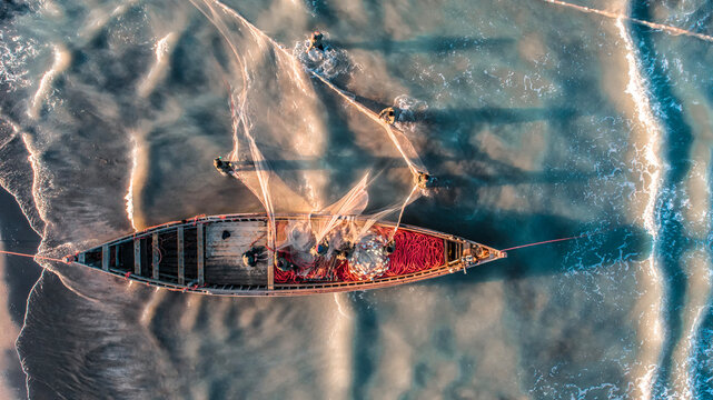 Drone view of a fishing boat with fishermen casting nets