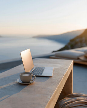 Sunset bathes a minimalist table beside a sea view. Open laptop sits ready for work or thought. Cup of coffee rests nearby, warm and quiet. Serene atmosphere suggests peace or focus
