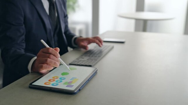 パソコンとタブレットPCを使って作業する男性。DX、IT、ビジネス、オフィス、仕事、作業、デザイン
