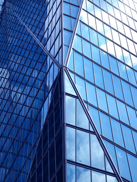 Urban skyscraper with mirrorlike surfaces showcasing clouds and geometric patterns