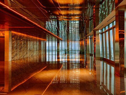 Spacious glass atrium with reflections on polished floor and panoramic windows. Empty lobby features