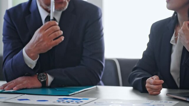 Male and female business professionals holding a meeting while reviewing documents. Consultation, business negotiations, management, teamwork, marketing, and mentoring.
