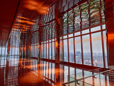 Spacious glass atrium with reflections on polished floor and panoramic windows. Empty lobby features
