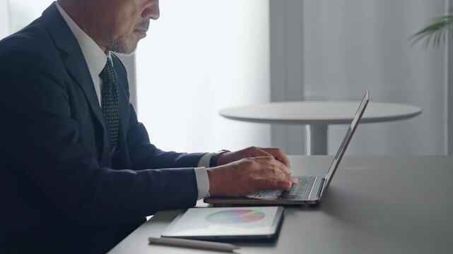 ノートパソコンとタブレットPCを使って作業する男性。DX、IT、ビジネス、オフィス、仕事、事務、業務