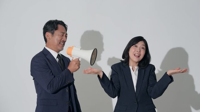 拡声器で女性に注意する男性ビジネスパーソン。注意、指示、指導、無視、叱る、上司、部下、叫ぶ、不満