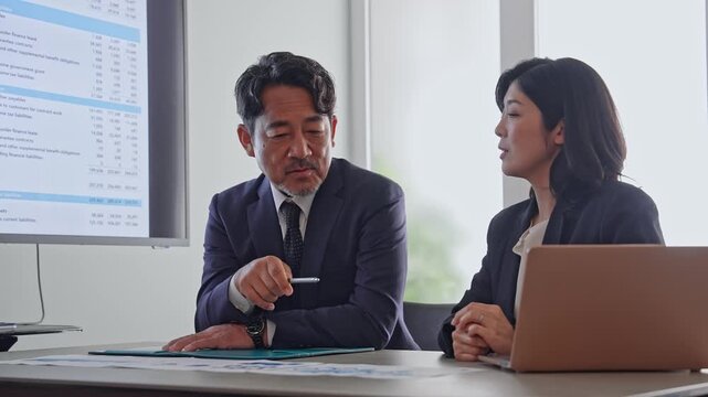 書類を見ながら会話するビジネスパーソンのグループ。会議、ミーティング、相談、チームワーク、経営、人材