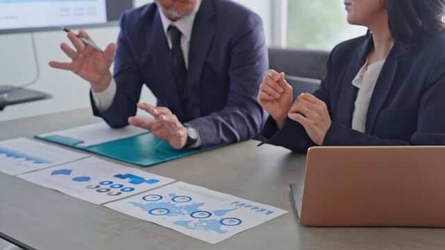 書類を見ながら会話するビジネスパーソンのグループ。会議、戦略、経営、チームワーク、相談、商談、会話