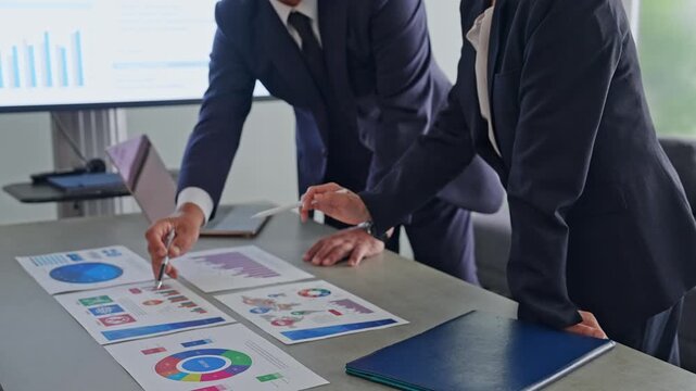 A group of business professionals conversing while looking at documents. Meetings, management, strategy, corporate, data, marketing.