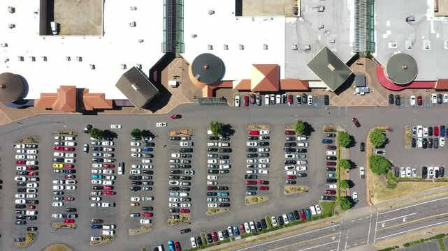 4K aerial drone footage of a busy outlet shopping center in Woodburn, Oregon, USA during the Juneteenth holiday with crowded parking lots, retail stores, and shoppers