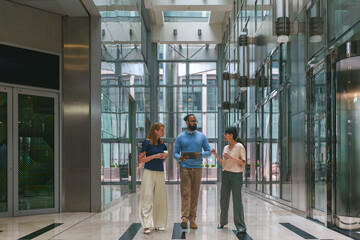 Fototapeta premium Diverse business colleagues walking and collaborating in a contemporary glass office building