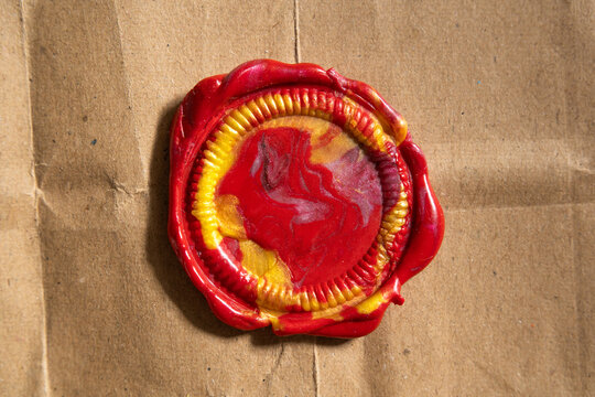 Vintage Red Wax Seal Stamp with Golden Color Fills on Textured Brown Kraft Paper Background