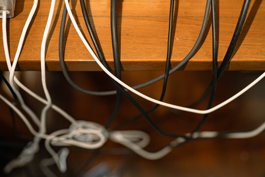 Tangled and Messy Computer Power Cables and Wires Behind a Home Office Working Desk Setup