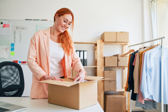 Young woman packing order box in small clothing business