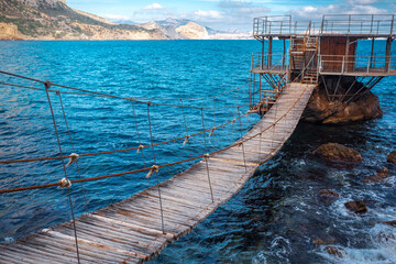 Obraz premium Wooden Rope Suspension Bridge Over the Blue Sea to a Platform