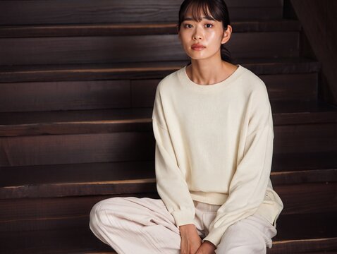 Young Woman Sitting Indoors in Casual Wear with Thoughtful Expression