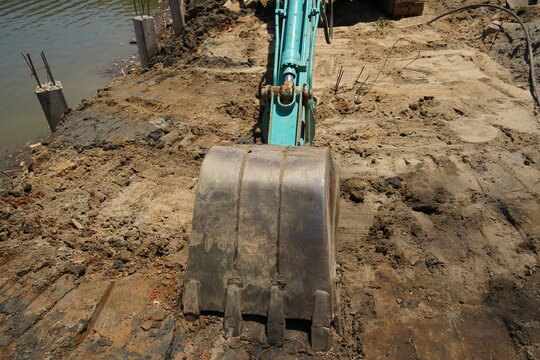 Building process city levee. Excavator dredging pond bank