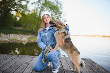 Fototapeta premium Woman petting her dog on a wooden dock