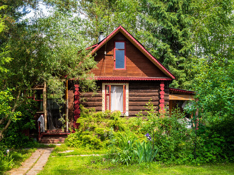 wooden log rustic house on green lawn among trees