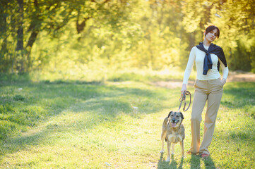 Fototapeta premium Woman walking dog in park during sunny spring day