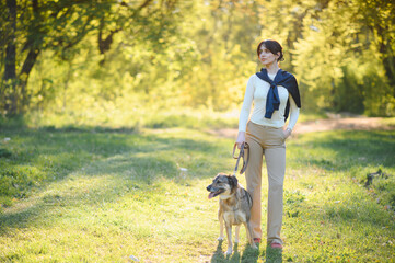 Fototapeta premium Woman walking dog through park enjoying sunny afternoon