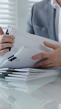 Business professional hands actively managing a large stack of office documents. Reports. And paperwork. Representing administrative work. Corporate bureaucracy