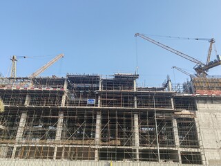 High rise under construction building with their incomplete structure. tall building with their tower crane erected beside it and having scaffolding around the building. concrete structure tower  © Usama