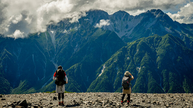 大パノラマを眺める二人の登山者の後ろ姿